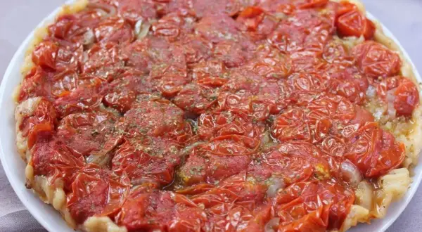 Tarte tatin di pomodorini confit, con cipolle caramellate e erbe aromatiche, un tripudio di sapori mediterranei.