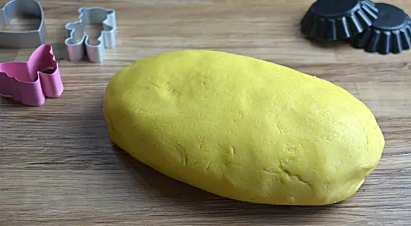 Impasto giallo per pasta frolla Bimby pronto per essere trasformato in biscotti con formine a orsetto, cuore e farfalla.