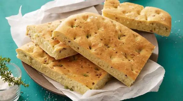 Focaccia con lievito istantaneo, dorata e soffice, guarnita con erbe aromatiche e sale grosso. Perfetta per un pasto veloce e gustoso.