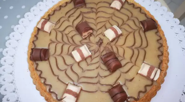 Torta Kinder Bueno con decorazione a ragnatela e pezzi di cioccolato.