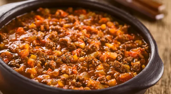 Un saporito ragù di cinghiale in una ciotola di terracotta, pronto per essere gustato con la pasta.