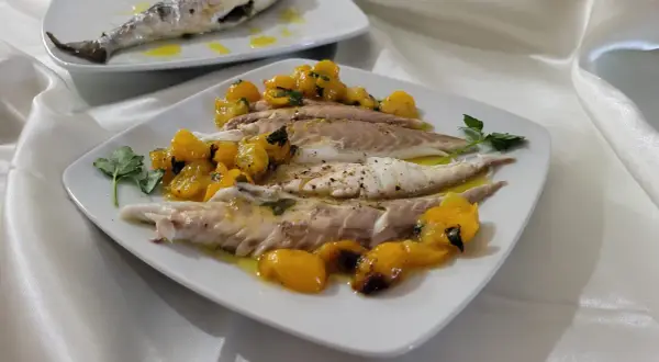 Orata in friggitrice ad aria, servita con pomodorini gialli e prezzemolo. Un piatto leggero e gustoso.