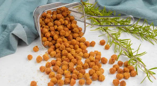 Ceci croccanti in friggitrice ad aria, appena usciti dal cestello, con rametti di rosmarino fresco.