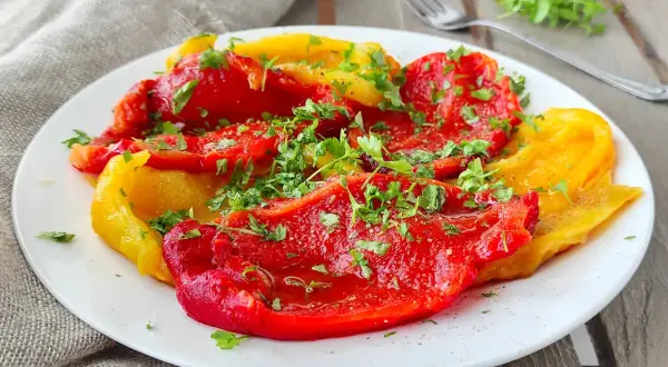 Peperoni rossi e gialli cotti in friggitrice ad aria, conditi con prezzemolo fresco. Un contorno saporito e leggero.