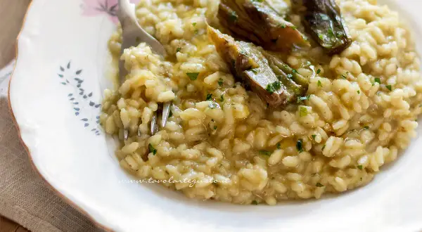 Un cremoso risotto con carciofi freschi, guarnito con prezzemolo tritato e un filo d'olio.