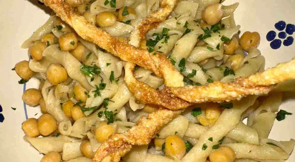 Piatto di ciceri e tria, pasta fresca con ceci e croccanti sfoglie fritte, guarnito con prezzemolo tritato.