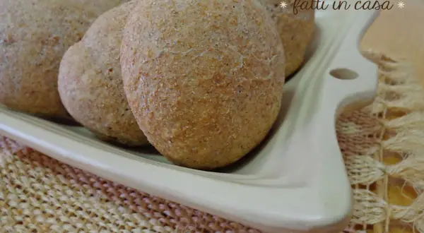 Panini integrali fatti in casa, morbidi e fragranti, serviti su un piatto bianco.