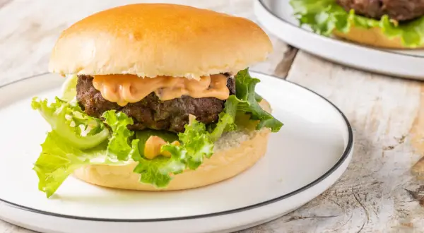 Hamburger succulento con salsa, lattuga croccante e panino soffice, preparato in friggitrice ad aria.