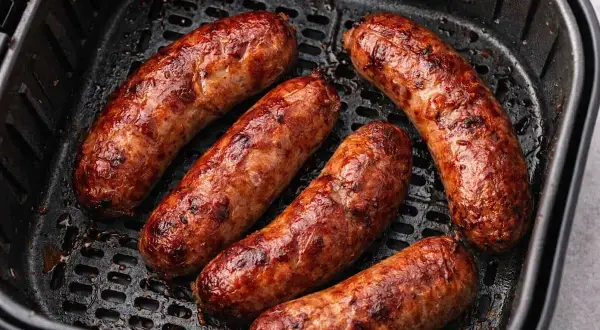 Salsiccia dorata e succulenta in friggitrice ad aria, pronta per essere gustata.