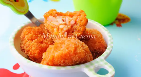 Polpette di riso dorate e croccanti, con un cuore filante di formaggio, servite in una ciotola a quadretti.