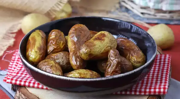 Patate novelle dorate e croccanti, appena sfornate dalla friggitrice ad aria, servite in una ciotola scura.