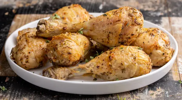 Cosce di pollo dorate e succulente, cotte alla perfezione nella friggitrice ad aria, guarnite con erbe aromatiche fresche.