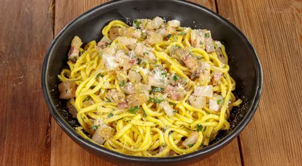 Spaghetti alla chitarra conditi con guanciale croccante, pecorino e prezzemolo fresco, un piatto che sa di tradizione.