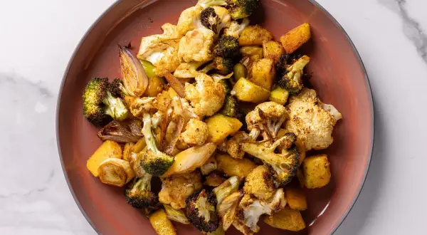 Un piatto di verdure miste, tra cui broccoli, cavolfiore e patate, cotte in friggitrice ad aria, con un aspetto dorato e appetitoso.