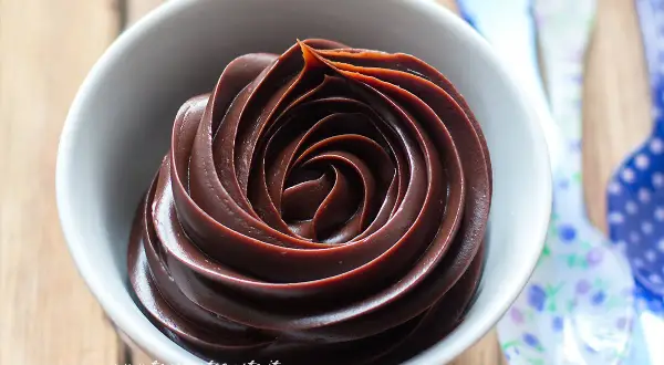 Una spirale perfetta di ganache al cioccolato in una ciotola bianca, pronta per essere gustata.