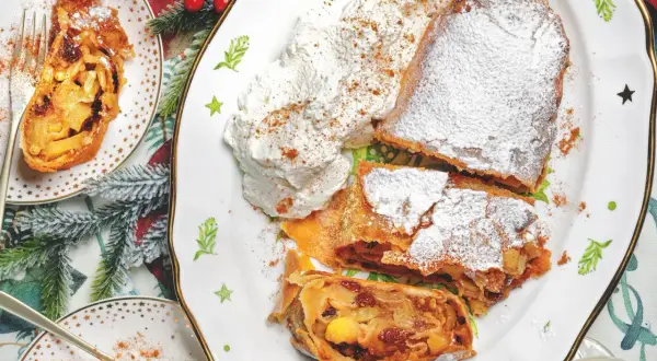 Delizioso strudel di mele, spolverato di zucchero a velo e servito con panna montata. Perfetto per la tua ricetta strudel di mele.