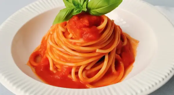 Un piatto di spaghetti al pomodoro fresco, guarnito con foglie di basilico profumato.