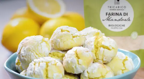 Biscotti con farina di mandorle, morbidi e profumati, pronti per essere gustati con limoni freschi sullo sfondo.