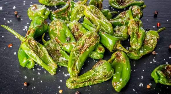 Friggitelli cotti in friggitrice ad aria, cosparsi di sale grosso e pepe nero, con qualche macchia di bruciatura che ne esalta il sapore.