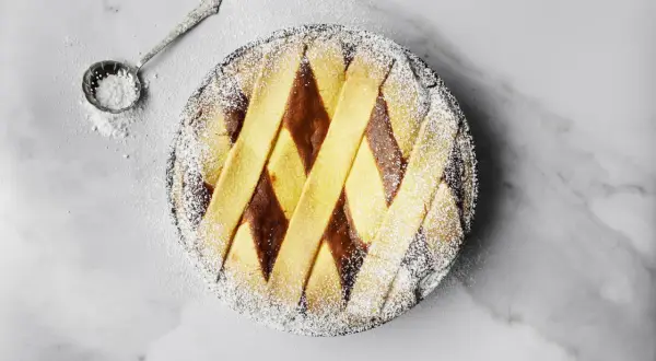 Pastiera napoletana pronta, cosparsa di zucchero a velo. Un assaggio di come si fa la pastiera, con la sua crostata decorata a rombi.