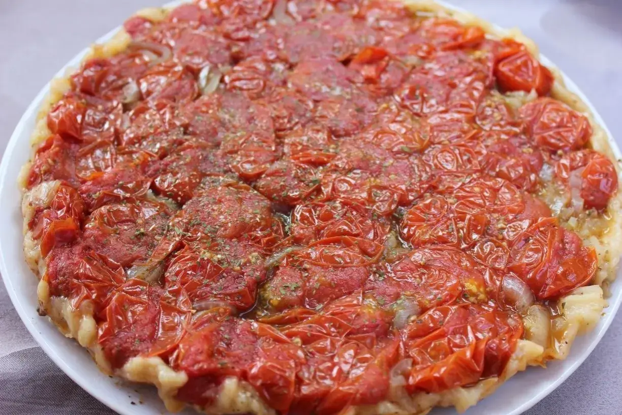 Tarte tatin di pomodorini confit, con cipolle caramellate e erbe aromatiche, un tripudio di sapori mediterranei.