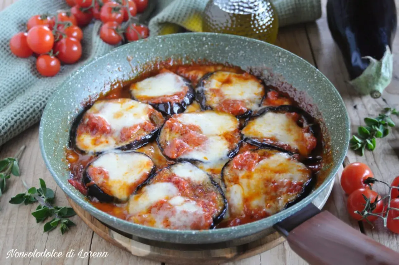 Fette di melanzane cotte in padella con pomodoro e mozzarella filante, un classico piatto di melanzane alla pizzaiola.