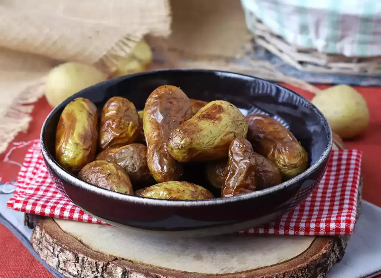 Patate novelle dorate e croccanti, appena sfornate dalla friggitrice ad aria, servite in una ciotola scura.