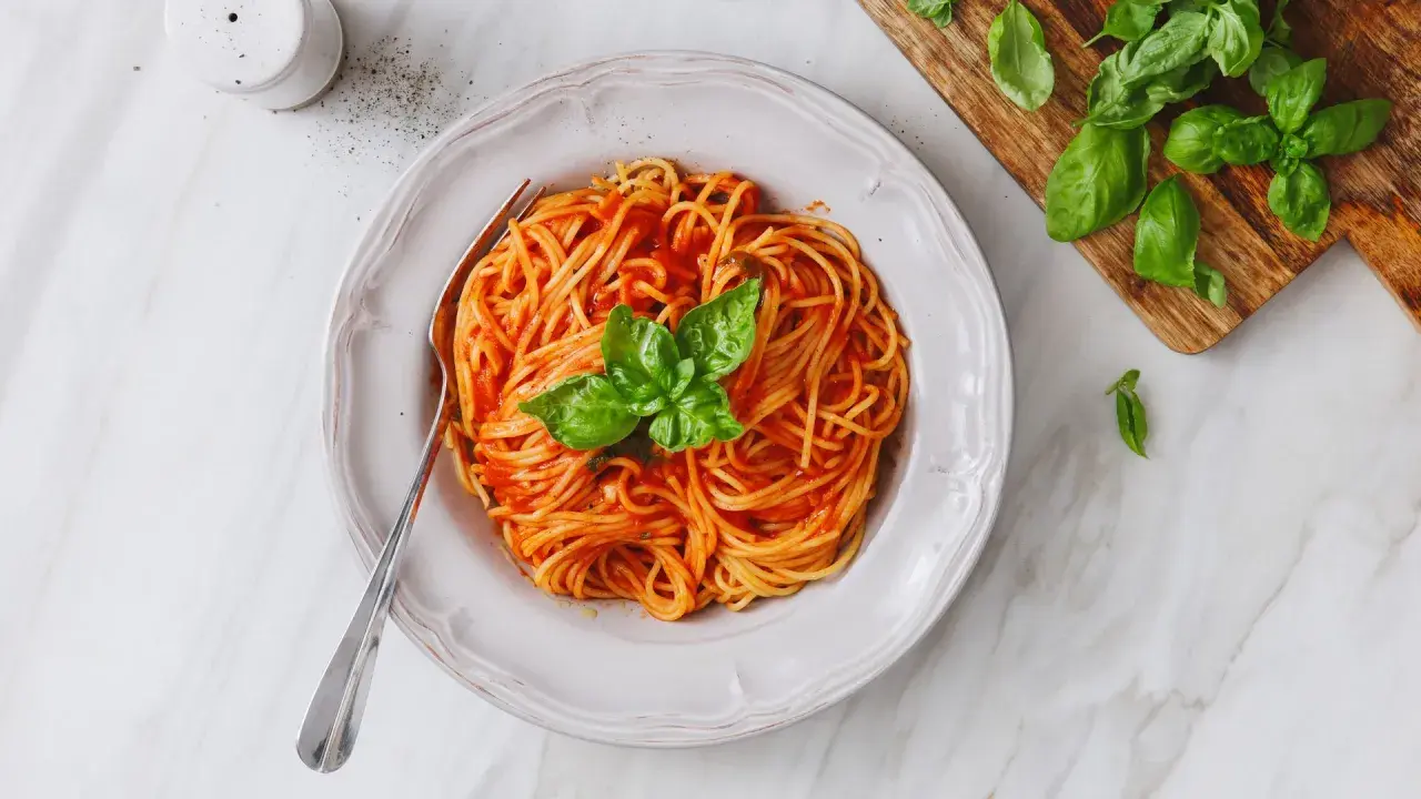 Un piatto di spaghetti al sugo di pomodorini freschi, guarnito con basilico, pronto per essere gustato.