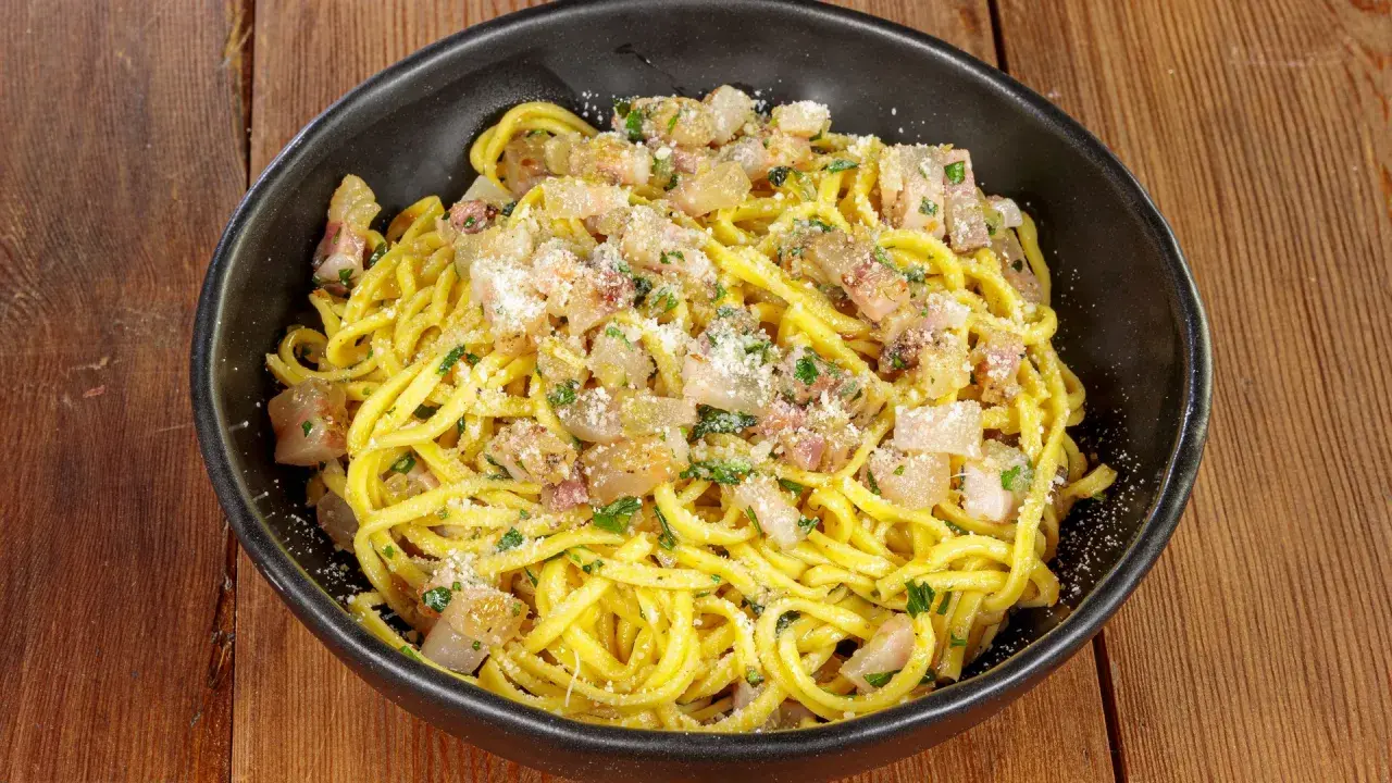 Spaghetti alla chitarra conditi con guanciale croccante, pecorino e prezzemolo fresco, un piatto che sa di tradizione.