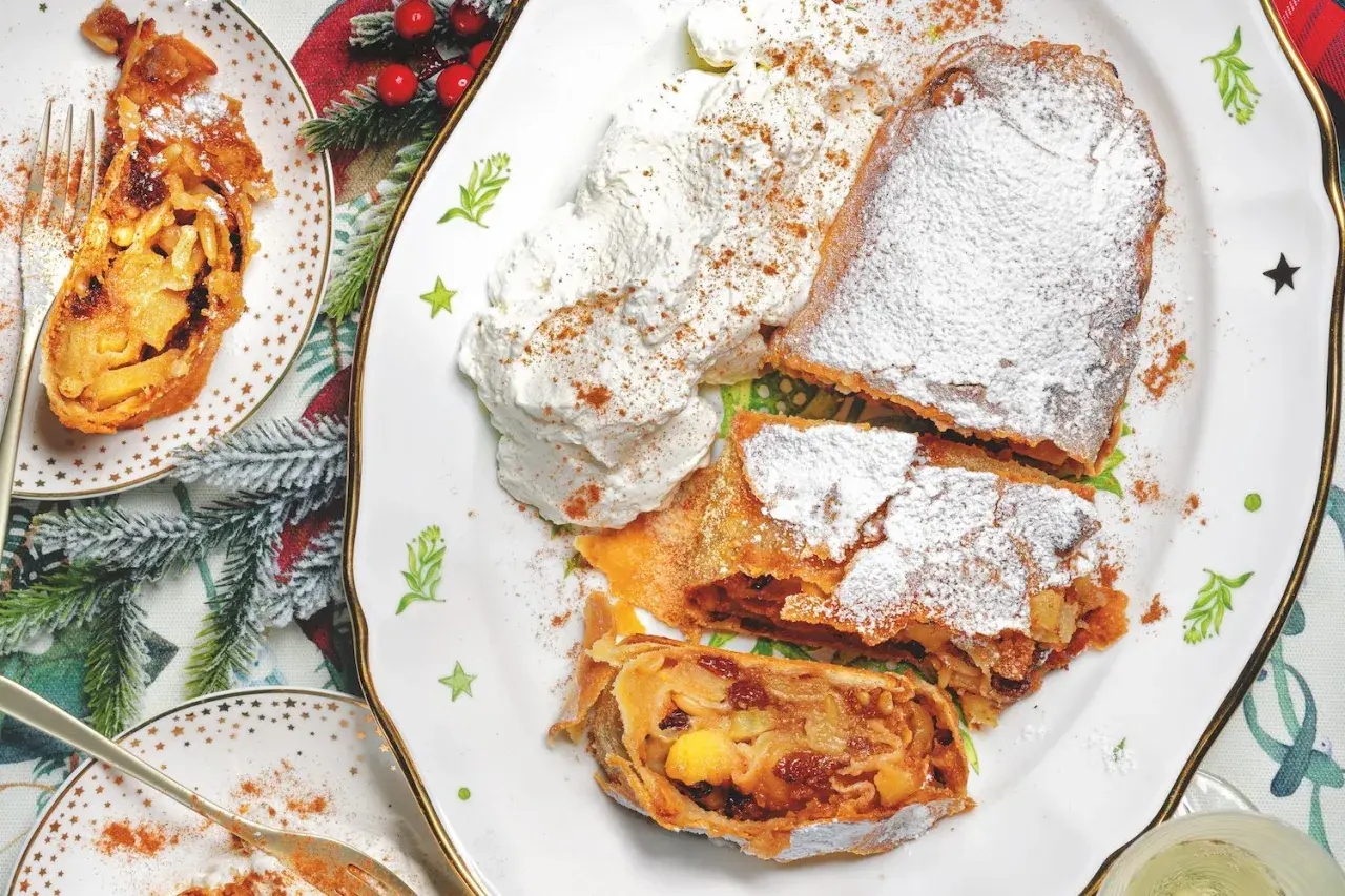 Delizioso strudel di mele, spolverato di zucchero a velo e servito con panna montata. Perfetto per la tua ricetta strudel di mele.