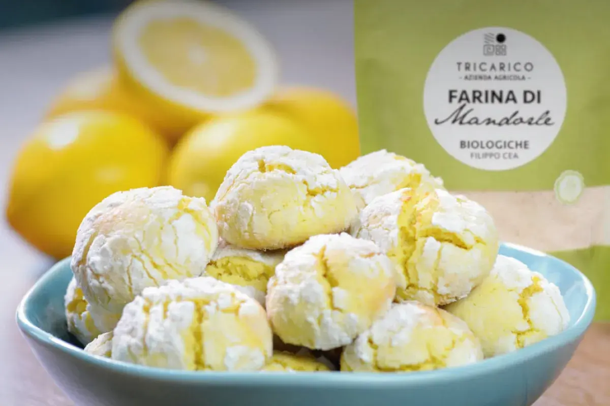 Biscotti con farina di mandorle, morbidi e profumati, pronti per essere gustati con limoni freschi sullo sfondo.