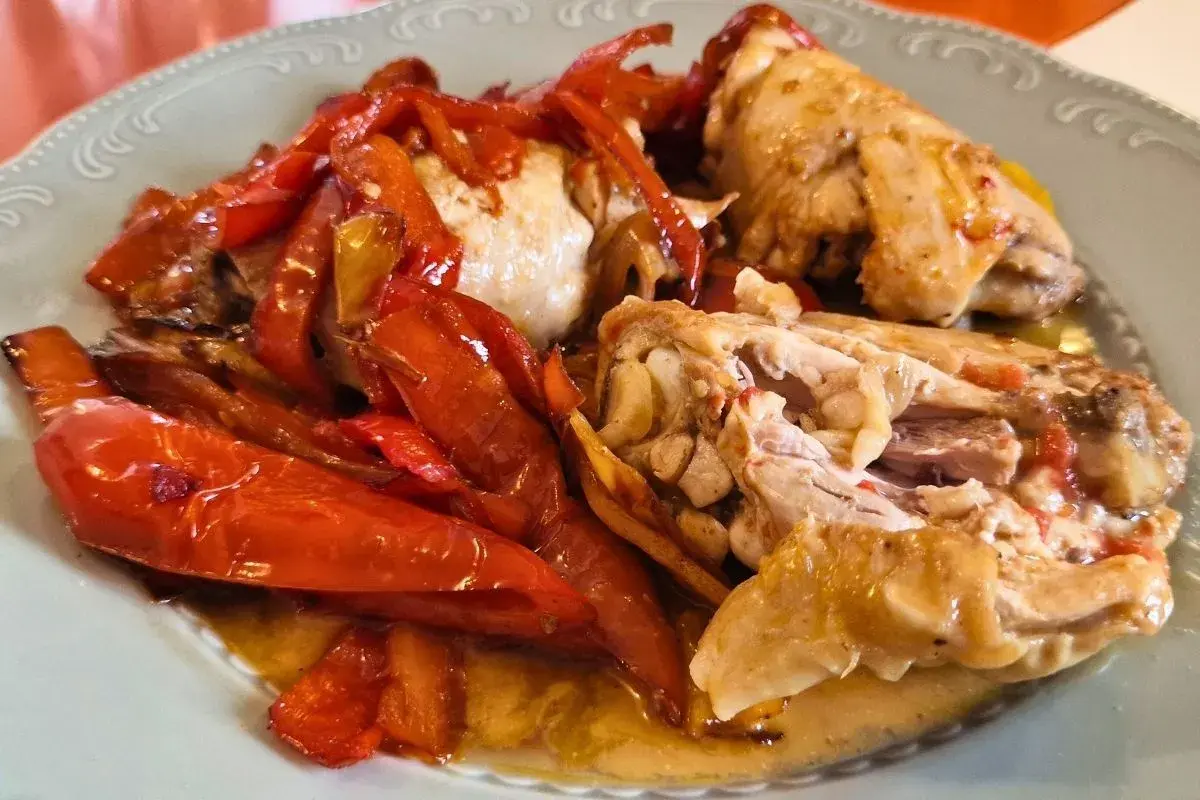 Pollo alla romana succulento con peperoni rossi arrostiti, servito su un piatto chiaro.