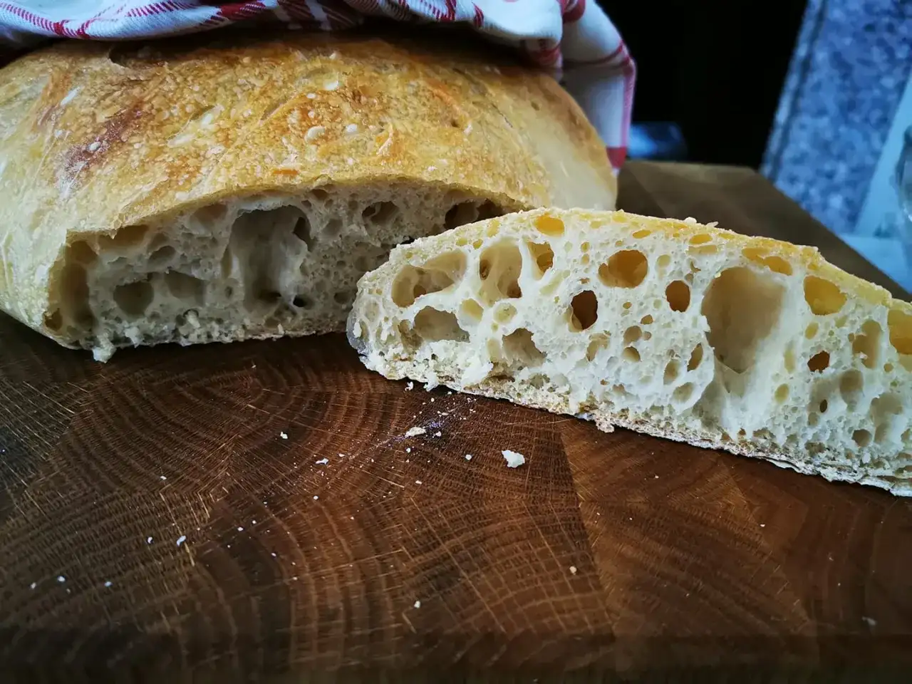 Pane fatto in casa, fragrante e alveolato, tagliato su un tagliere di legno.