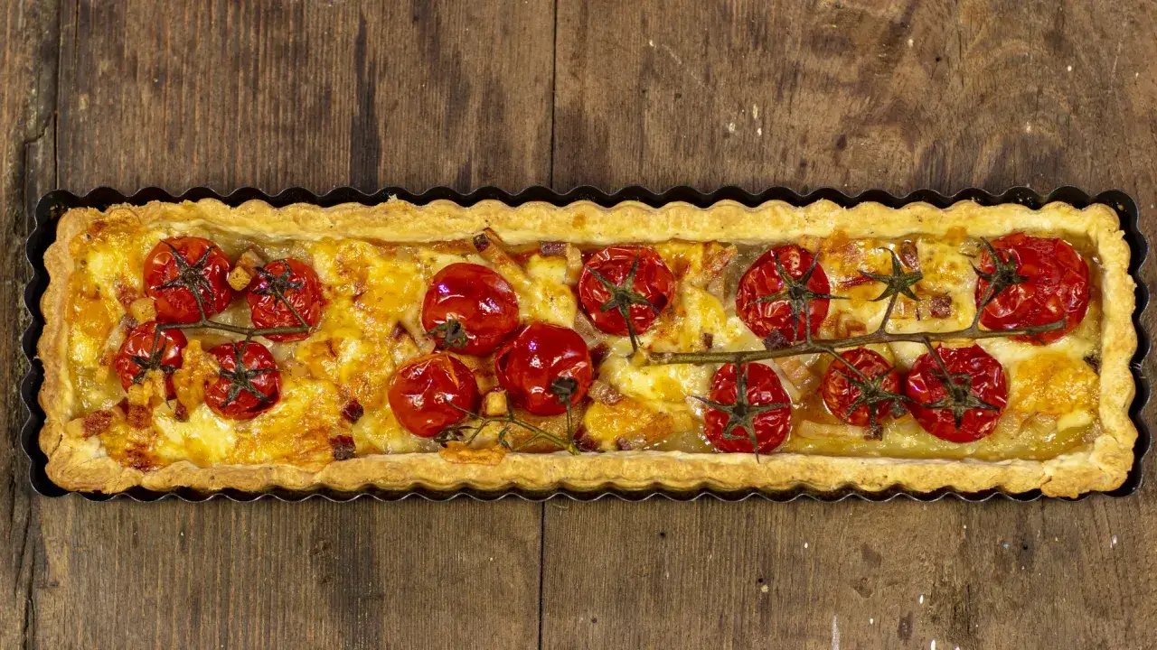 Tarte tatin di pomodorini ciliegino, dorata e invitante, con formaggio filante e pancetta croccante.
