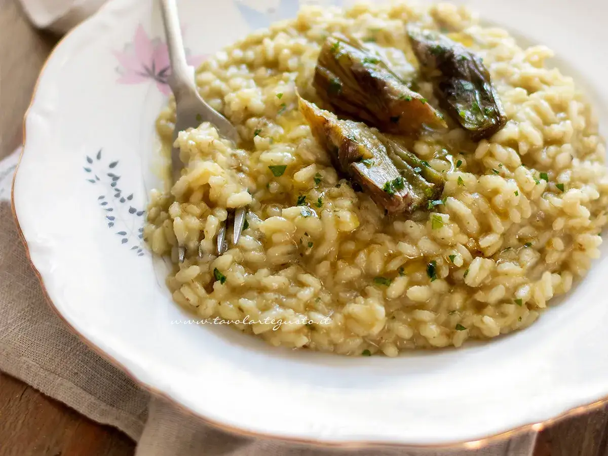 Un cremoso risotto con carciofi freschi, guarnito con erbe aromatiche e un filo d'olio.