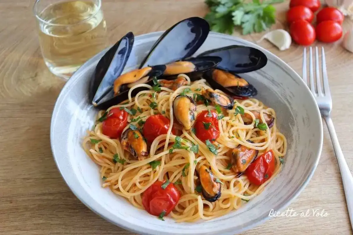 Spaghetti con le cozze e pomodorini, un piatto di pasta saporito e colorato, pronto per essere gustato.