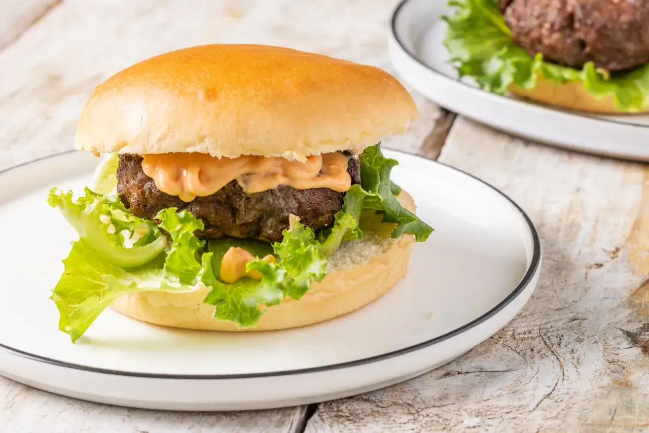 Hamburger succulento con salsa, lattuga e panino morbido, preparato in friggitrice ad aria.