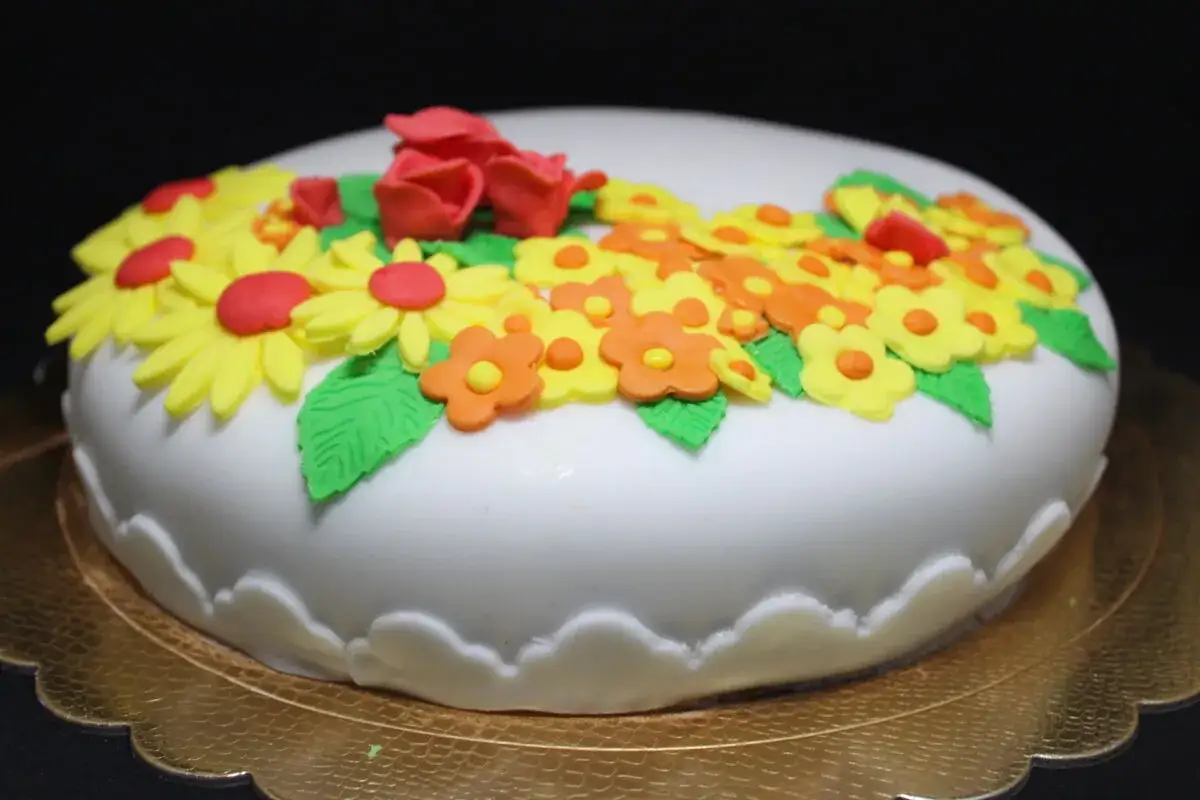 Torta bianca decorata con fiori colorati e rose in pasta di zucchero, un'esplosione di dolcezza primaverile.