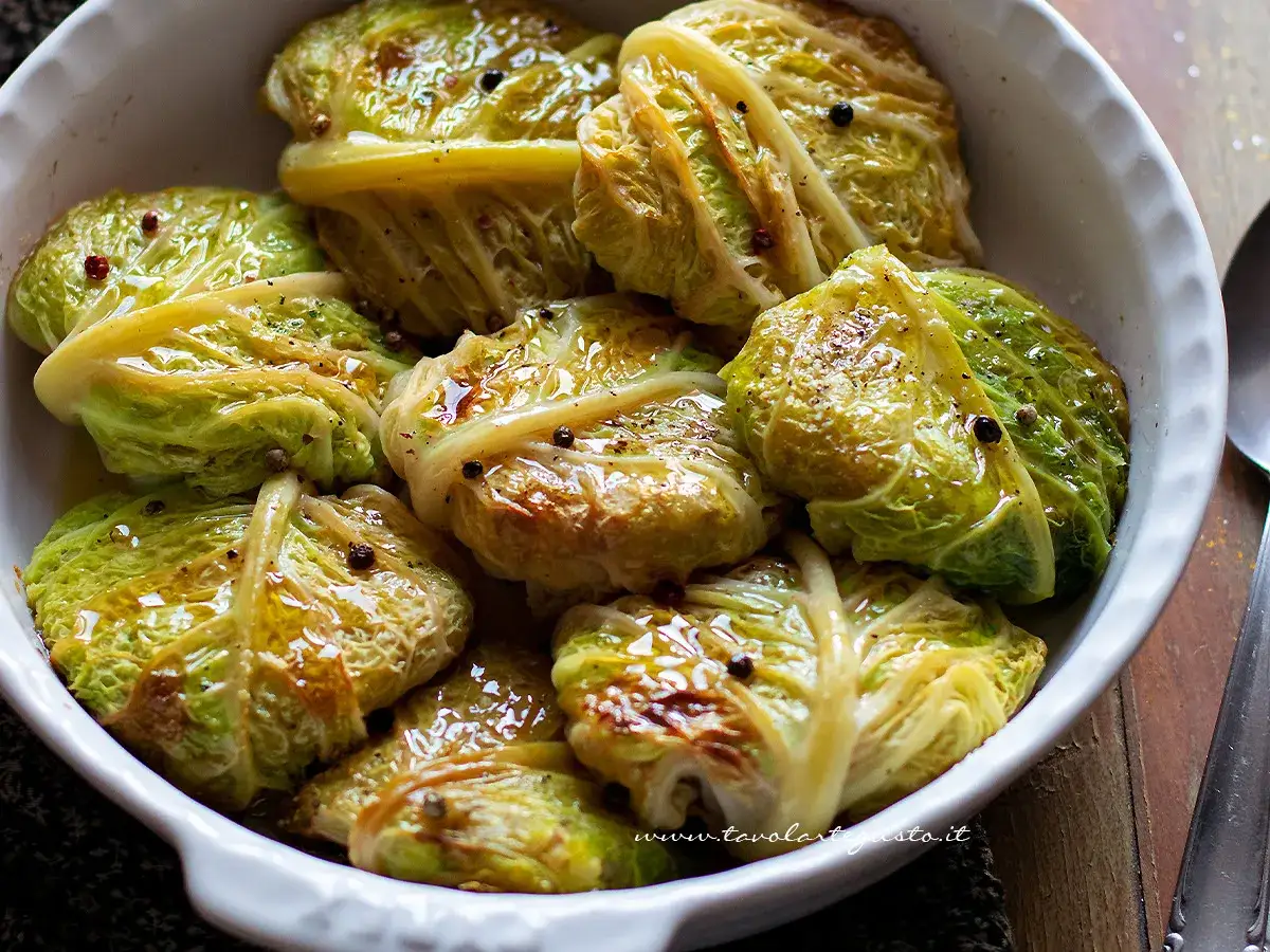 Involtini di verza succulenti, conditi con pepe nero e spezie, in una ciotola bianca.