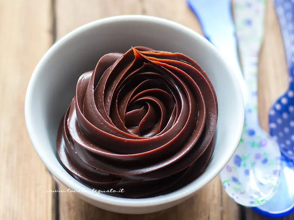 Una ciotola bianca piena di lucida ganache al cioccolato, disposta a spirale.