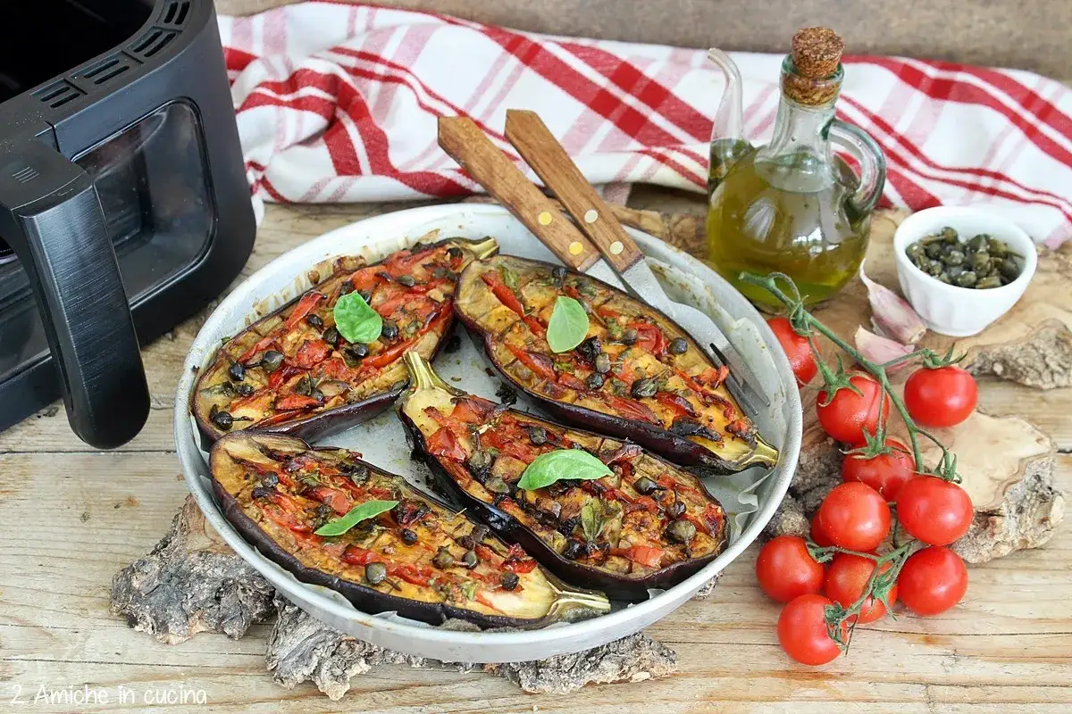 Melanzane ripiene cotte nella friggitrice ad aria, condite con pomodorini, capperi e basilico. Un piatto gustoso e leggero.