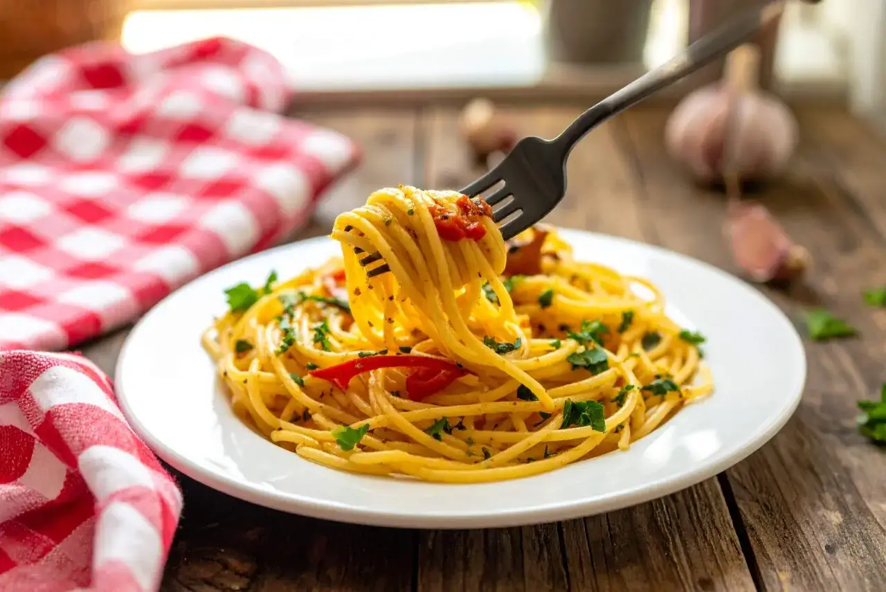 Un piatto di spaghetti alla carrettiera fumante, conditi con pomodoro, aglio e prezzemolo, pronti per essere gustati.