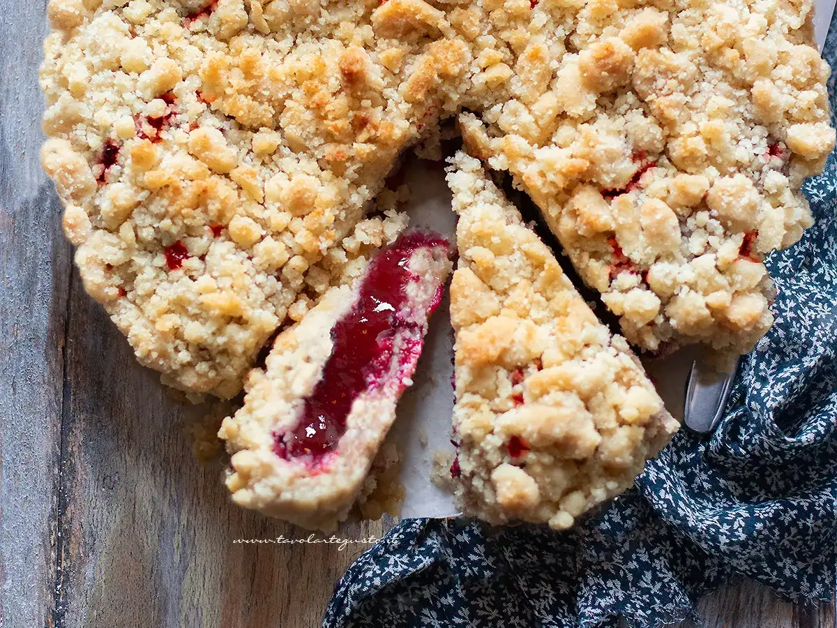 Una deliziosa sbriciolata alla marmellata, con la sua crosta dorata e il ripieno rosso brillante, pronta per essere gustata.