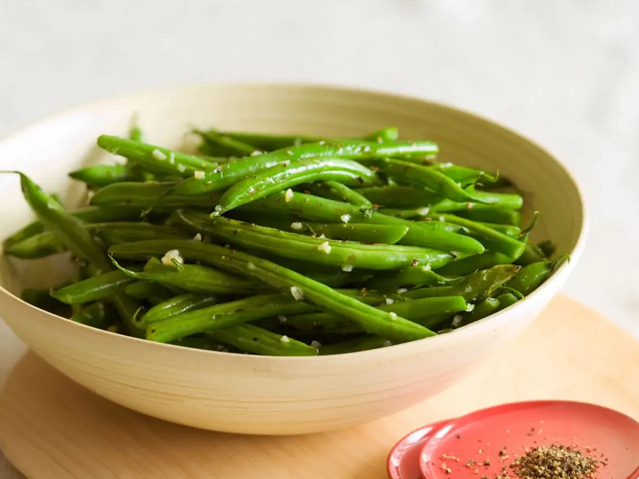 Fagiolini freschi saltati in padella con aglio e pepe, serviti in una ciotola di legno.