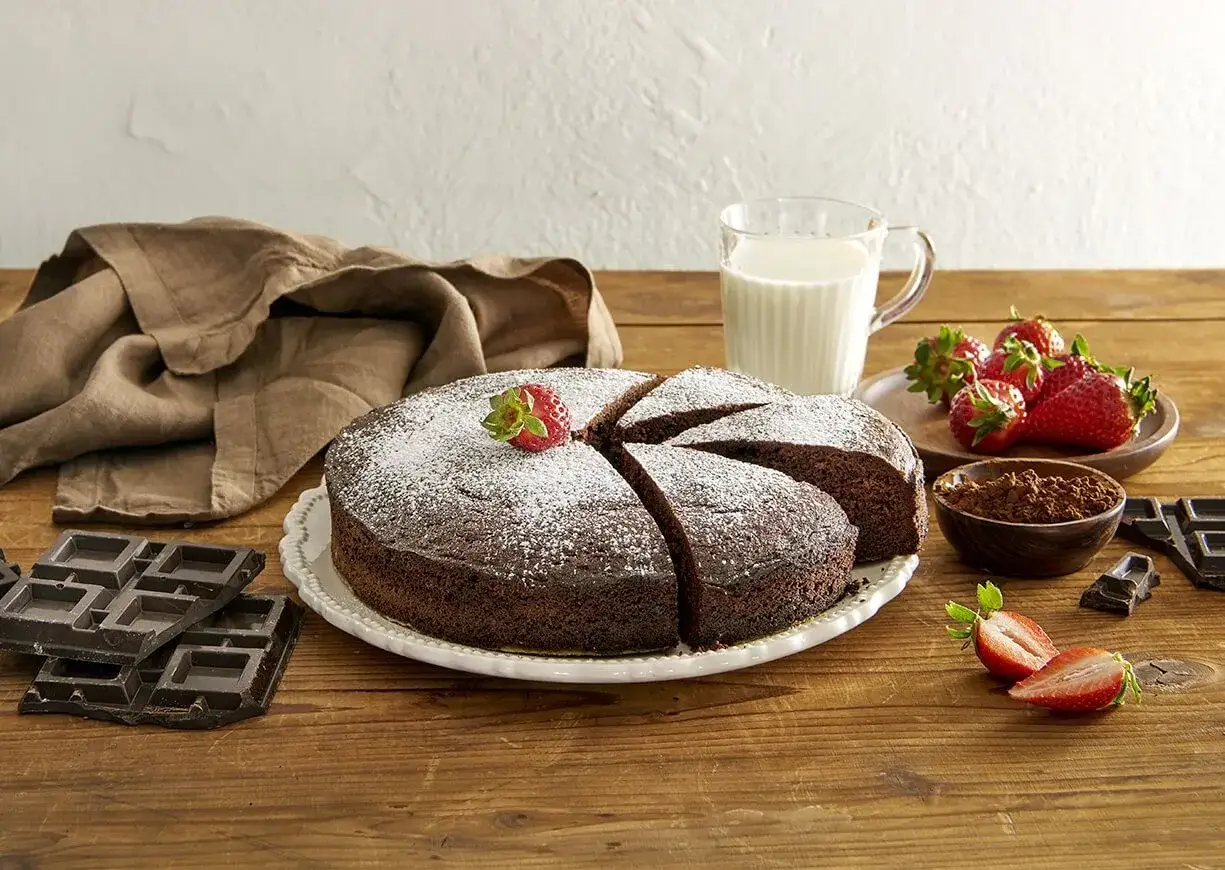 Delizioso pan di spagna al cacao, spolverato di zucchero a velo, con fragole fresche, cioccolato e un bicchiere di latte.