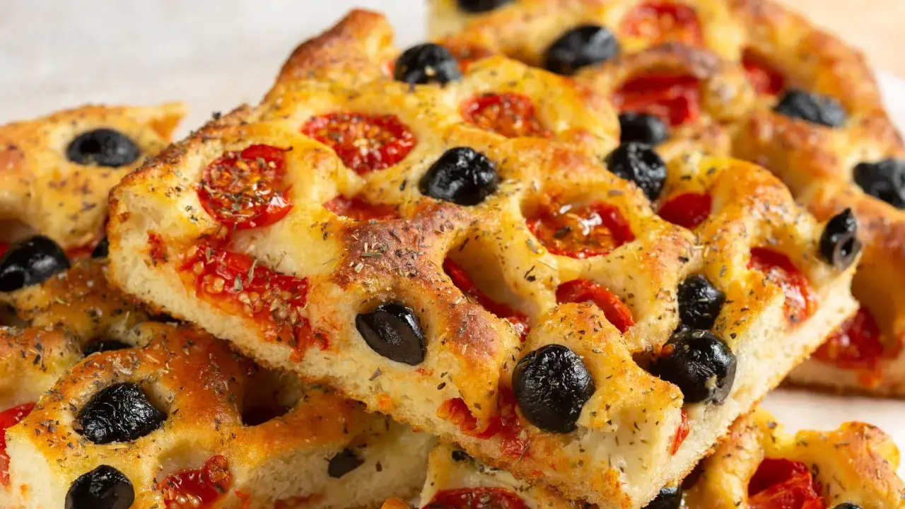 Focaccia pugliese ricetta originale sofficissima, con pomodorini e olive nere, dorata e profumata.