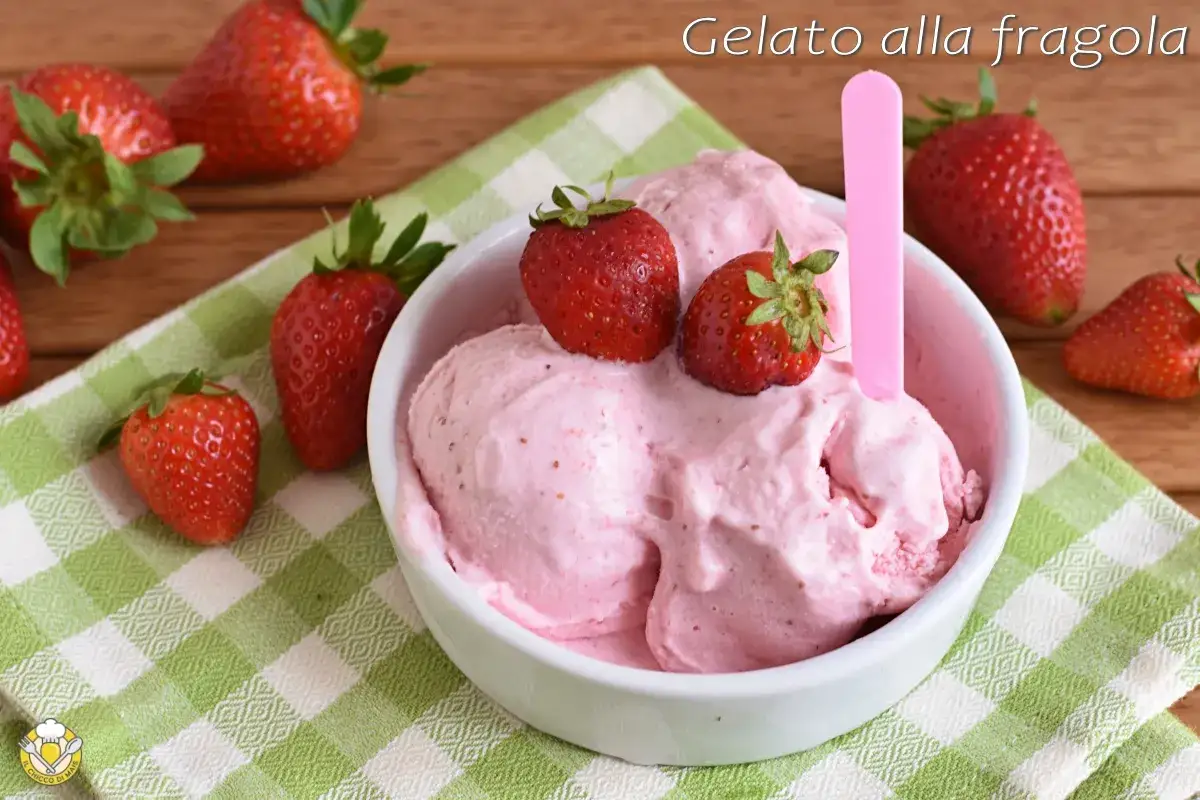 Una ciotola di cremoso gelato alla fragola, guarnito con fragole fresche, su una tovaglietta a quadri verdi.