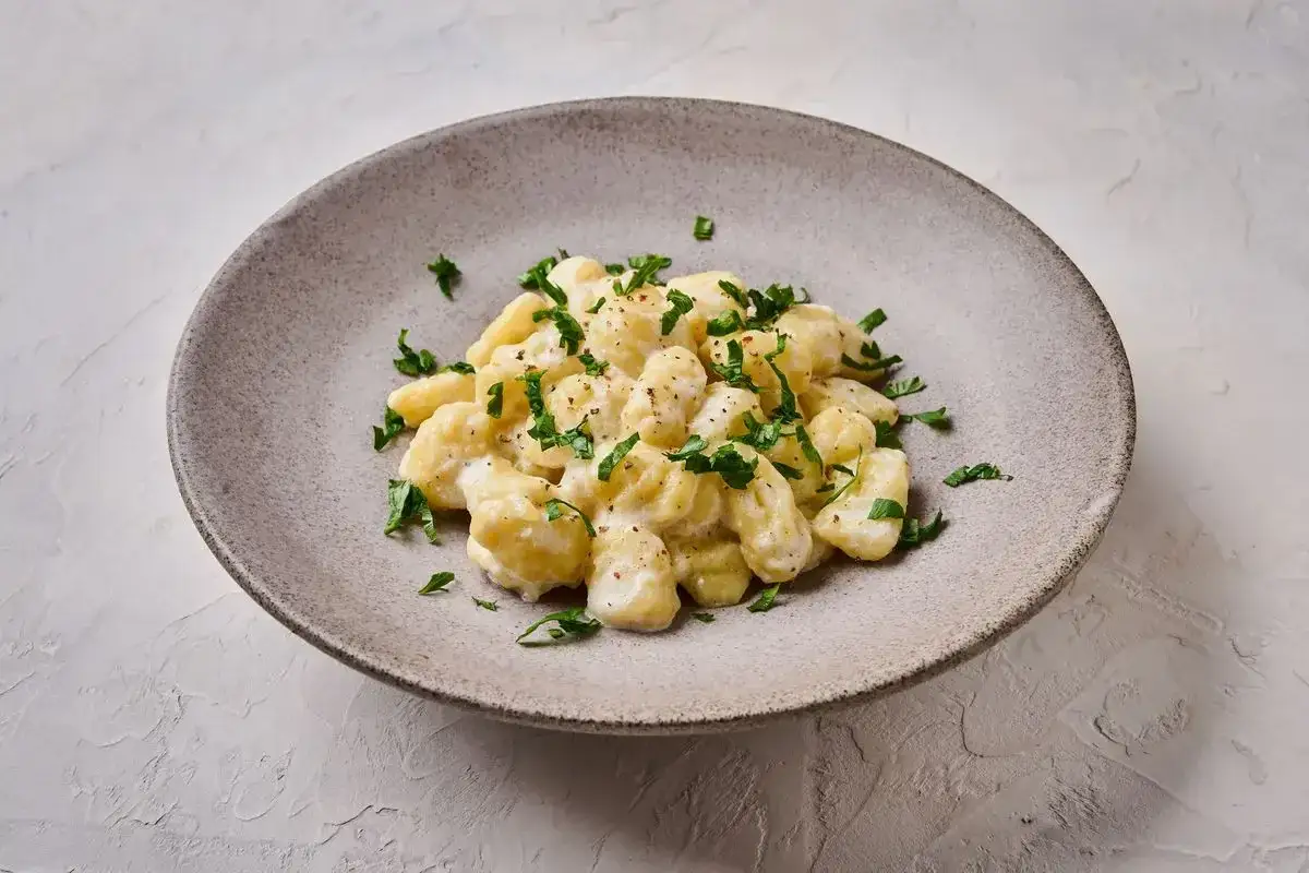 Gnocchi di ricotta soffici e cremosi, conditi con una salsa leggera e guarniti con prezzemolo fresco.