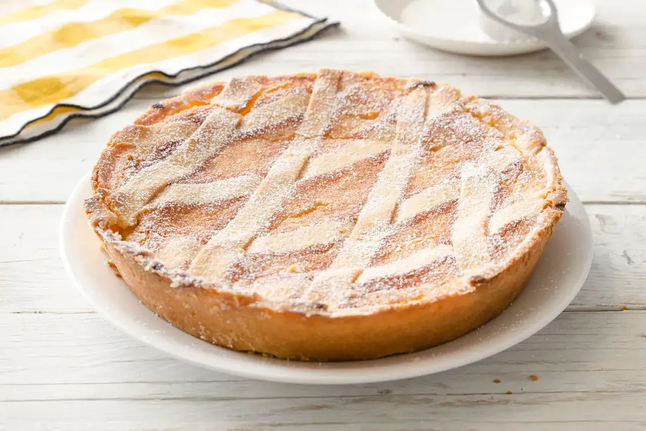 Pastiera napoletana pronta, un dolce tradizionale che mostra come si fa la pastiera con la sua crostata decorata a griglia e spolverata di zucchero a velo.