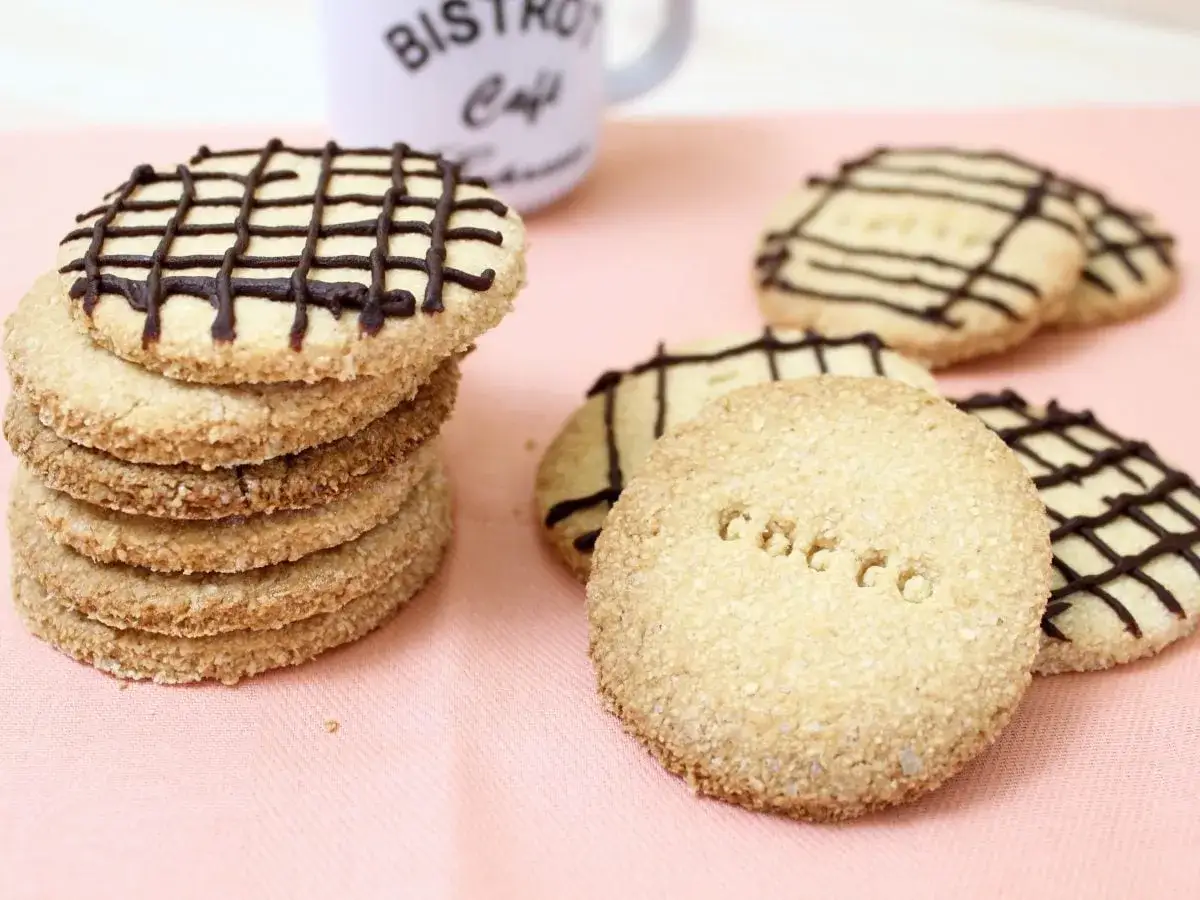 Biscotti al cocco, alcuni impilati e decorati con cioccolato, altri con la scritta 